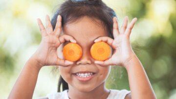 Mädchen mit zwei runden Karottenscheiben vor den Augen