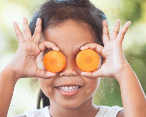 Mädchen mit zwei runden Karottenscheiben vor den Augen