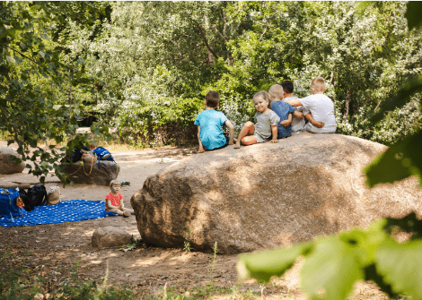 Kinder sitzen auf einem großen Stein